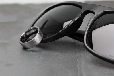 7mm wide tantalum, gunmetal colour, wedding ring resting against black sunglasses