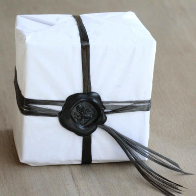 gift wrapped wedding ring box. The box is wrapped in tissue paper and carbon fibre with a black wax seal