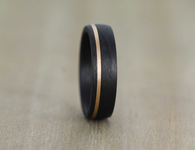 black carbon fibre wedding ring band. 6mm wide with a stripe of rose gold. black mans wedding ring uk