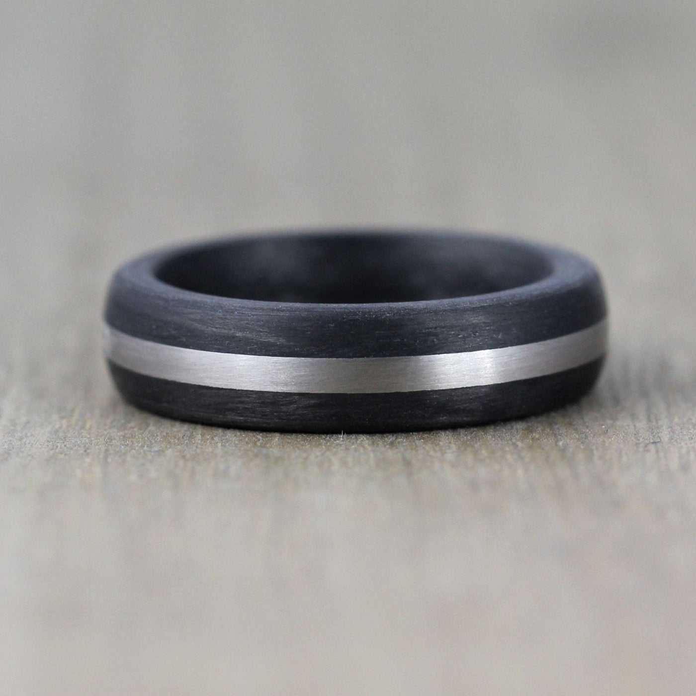 carbon fibre black wedding ring band with a palladium inlay. brushed finish 6mm wide court