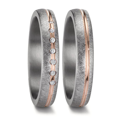 A matching wedding ring set crafted from tantalum and rose gold. The men's ring features a sleek, modern design with a central rose gold inlay, while the women's ring is adorned with five sparkling diamonds, complementing the warm rose gold accent set into the rich, dark tantalum