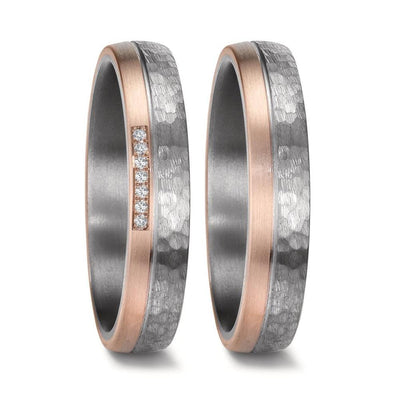 Matching wedding ring set crafted from hammered tantalum and 14K rose gold. The men's ring features a rugged matte-finish hammered tantalum band with a brushed rose gold edge, while the women's ring mirrors the design and is adorned with seven sparkling diamonds set into the rose gold accent. Both rings are 4.5mm wide with a comfortable fit, blending modern elegance with unique textures